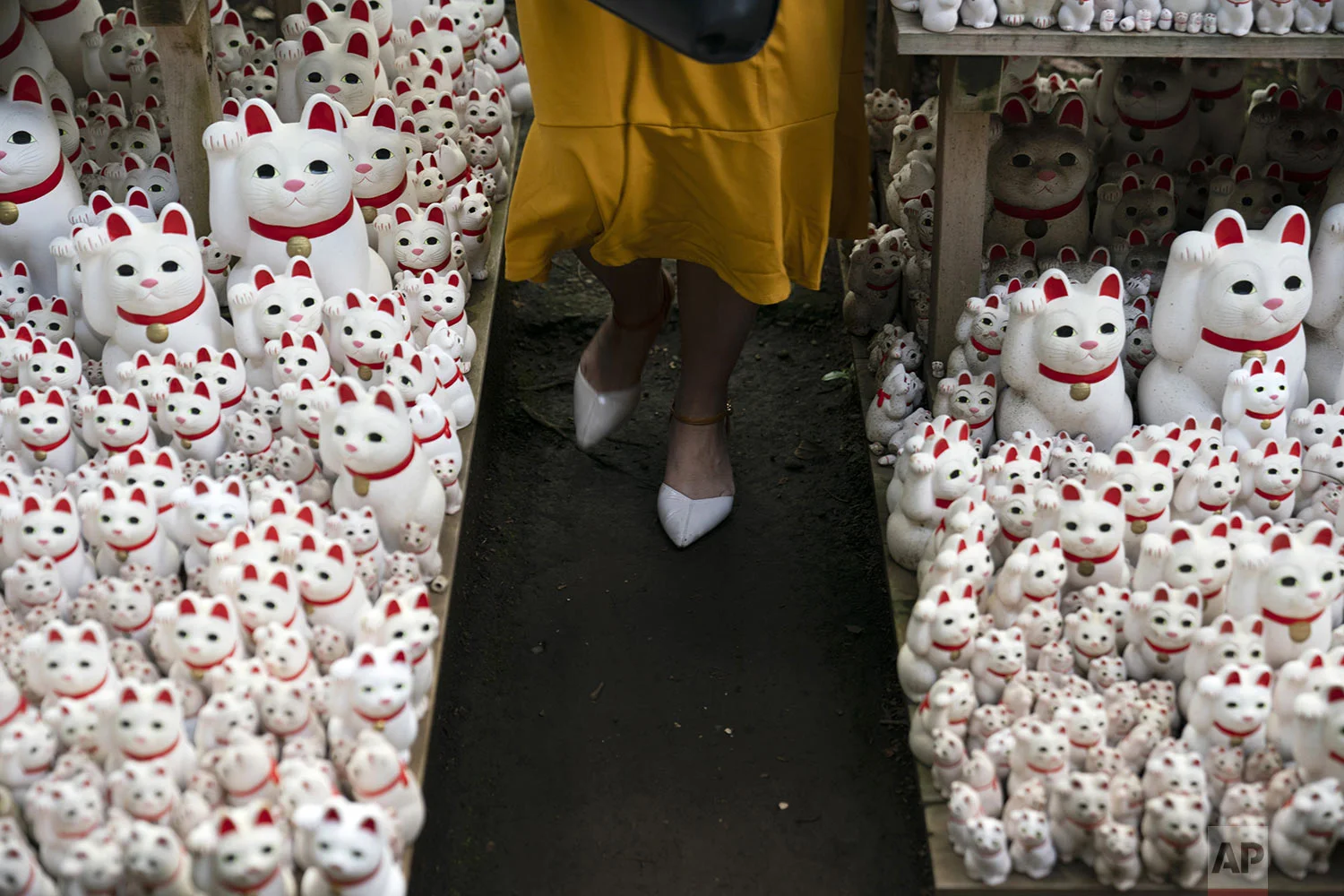 A tourist walk between beckoning cat figurines after posing for photos with them at Gotokuji Temple in Tokyo, Tuesday, June 25, 2019. (AP Photo/Jae C. Hong)