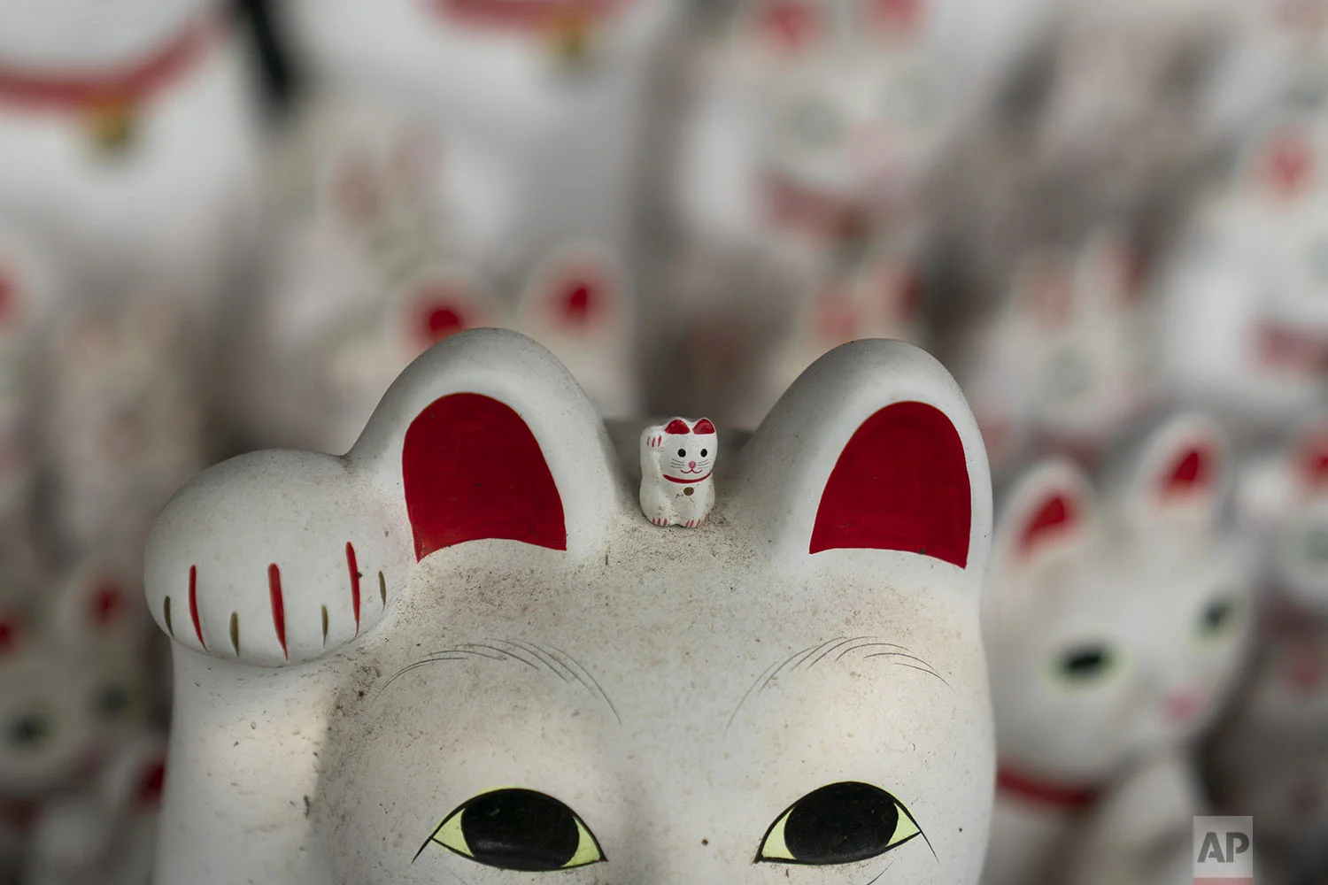 A small beckoning cat figurine is placed on top of a large statue at Gotokuji Temple in Tokyo, Tuesday, June 25, 2019. (AP Photo/Jae C. Hong)