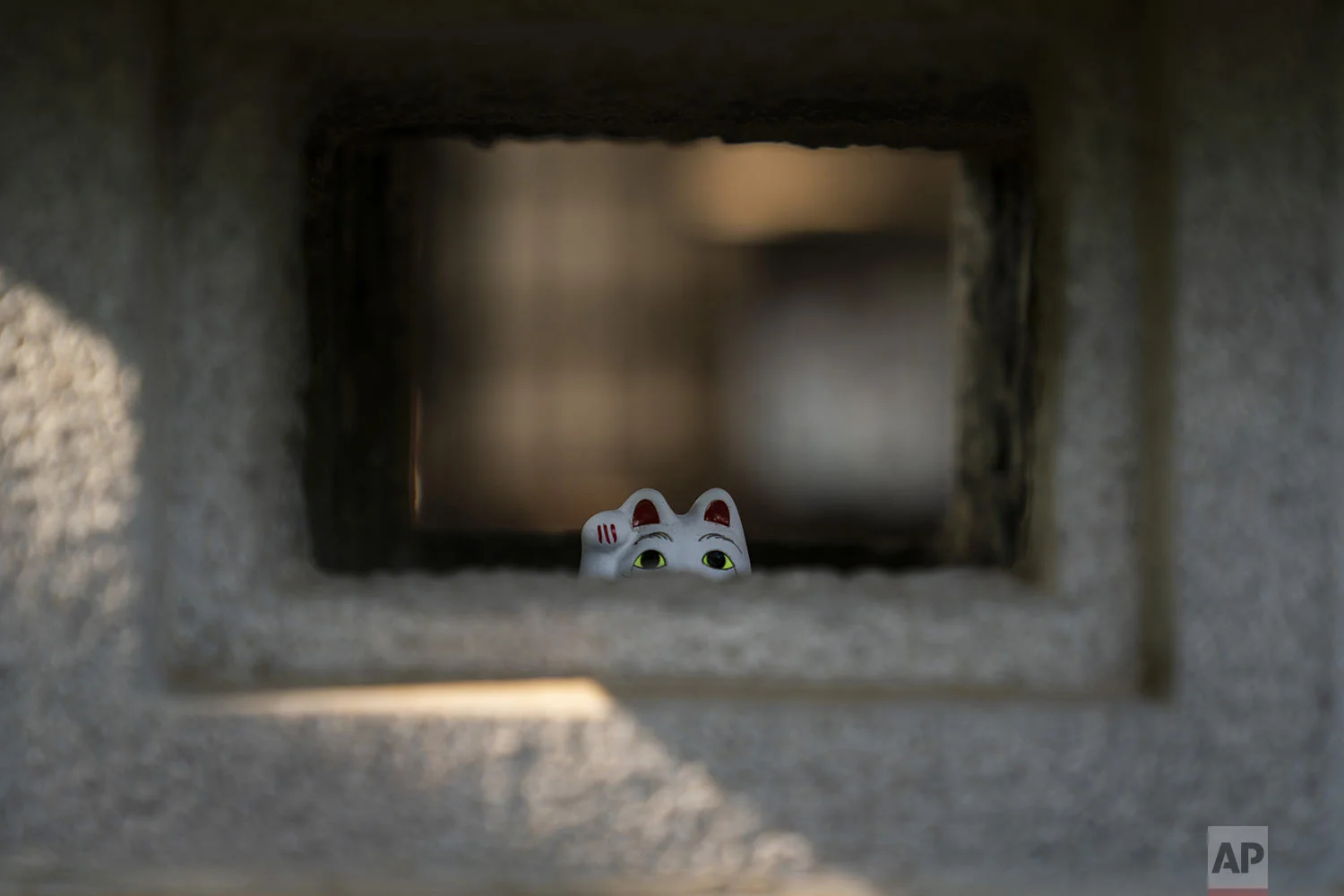 A small beckoning cat figurine is placed inside a stone lamp at Gotokuji Temple in Tokyo, Tuesday, June 25, 2019. (AP Photo/Jae C. Hong)