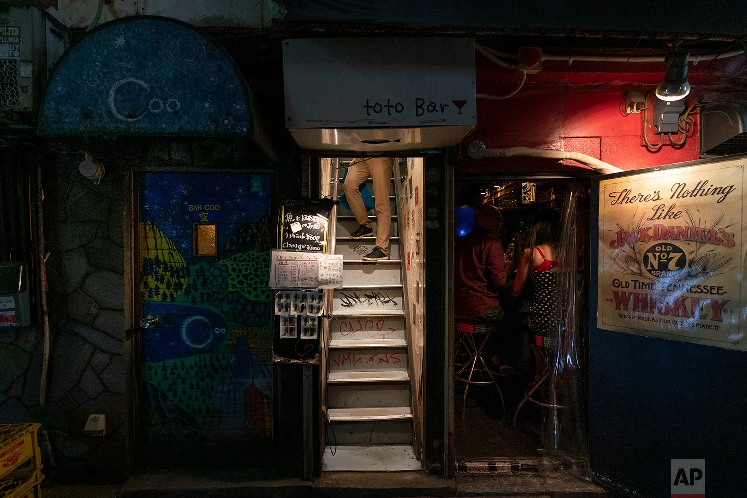 A man pauses briefly while walking down a narrow staircase of a bar in Golden Gai, in Tokyo, June 1, 2019. (AP Photo/Jae C. Hong)