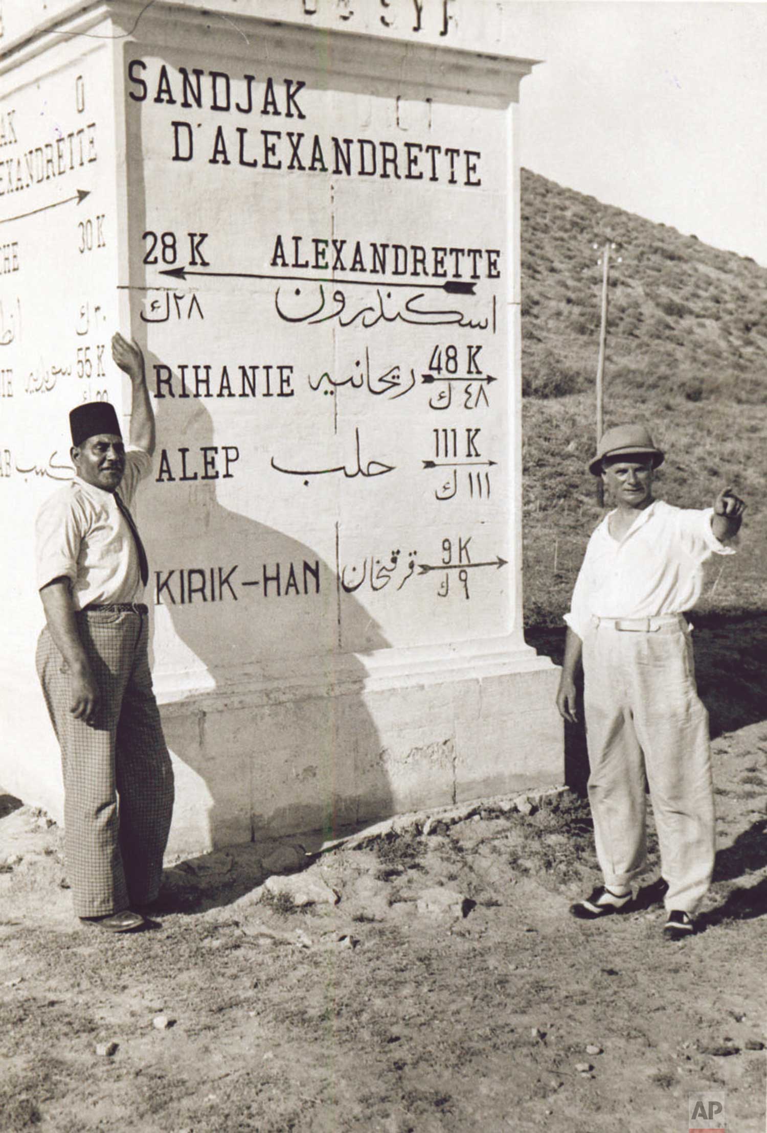Associated Press Foreign Correspondent James A. Mills (1883-1942), right, is pictured with an undentified friend beside a roadside mileage marker near Alexandrette in what is now Turkey, on September 2, 1938. At the time, Mills was reporting from the Middle East.