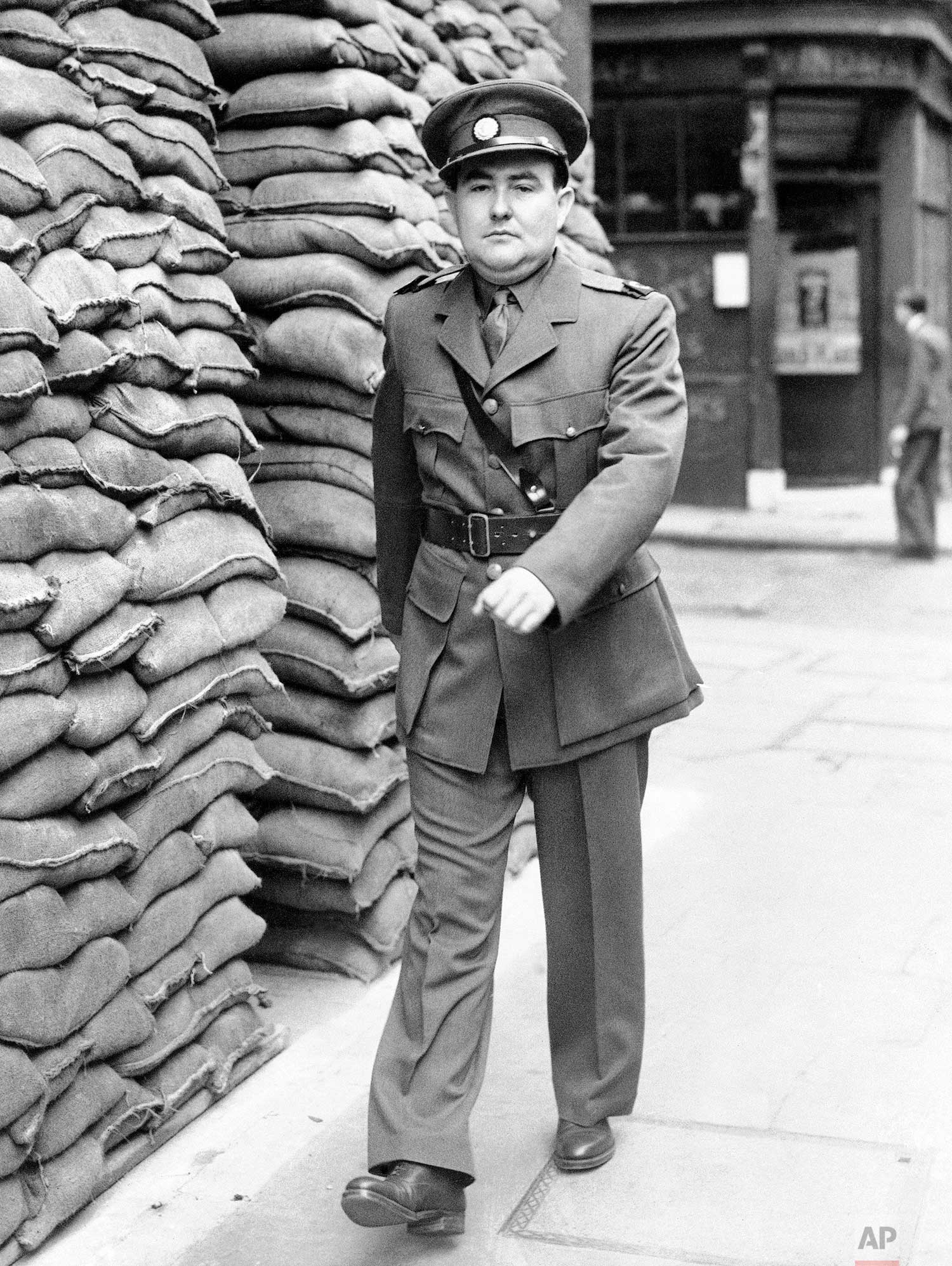 Drew Middleton, Associated Press reporter in London, has become a war correspondent and is to going to France next week, October 9-10th. He will wear the uniform of correspondents with the British Army: an officers uniform with special badges and a “Press” armlet. Drew Middleton, Associated Press correspondent is shown in his uniform passing the sandbagged Associated Press building in London on Oct. 24, 1939. (AP Photo)