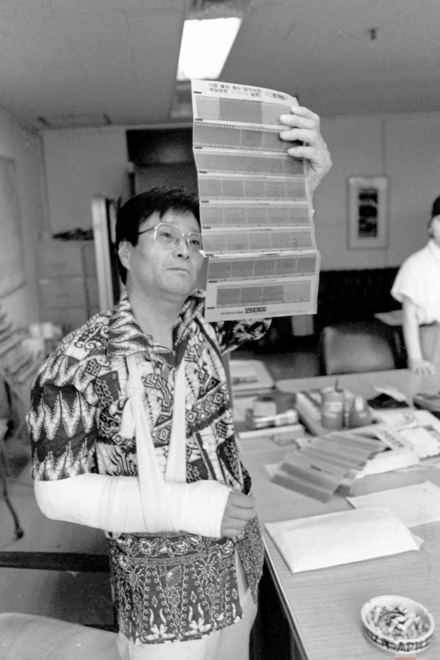 In this circa 1987 photo, AP photographer Kim Chon-kil looks at negatives at the Seoul, South Korea bureau. Kim suffered a broken arm when he was caught between rock-throwing students and riot police. (AP Photo/Corporate Archives)