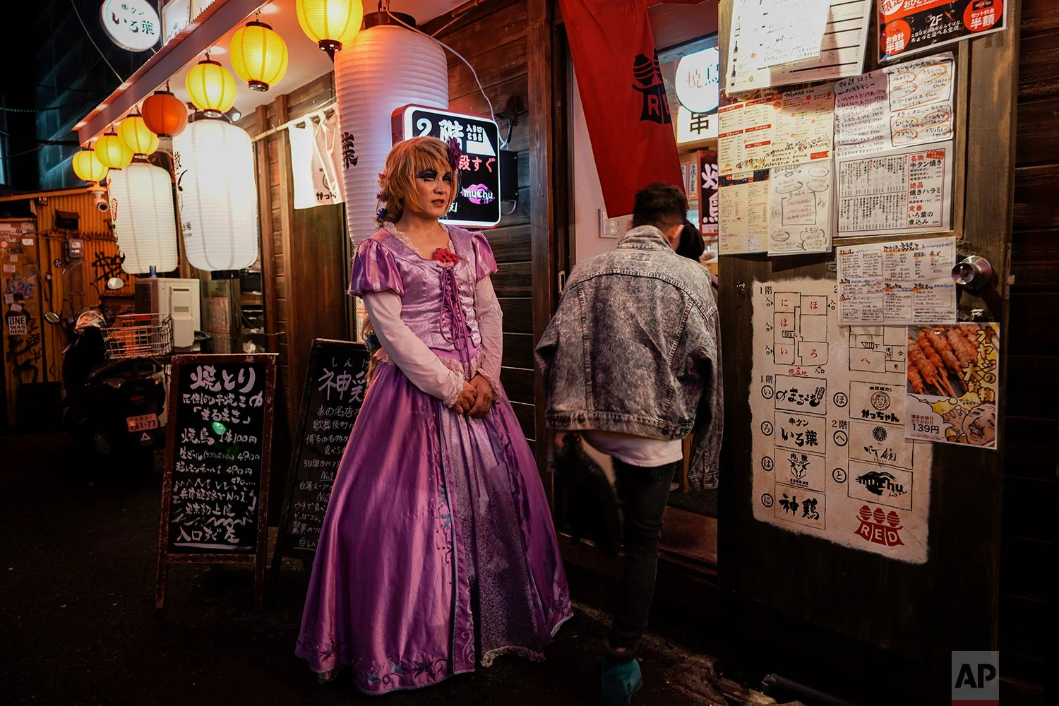 A restaurant worker wearing a princess-style dress greets customers at the entrance of a restaurant in the Shinjuku district of Tokyo, June 1, 2019. (AP Photo/Jae C. Hong)