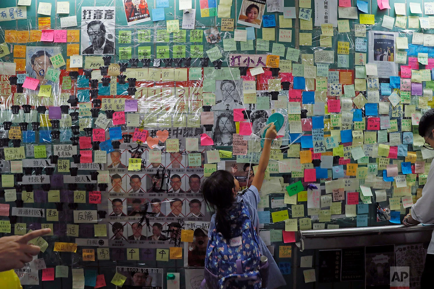 A child reaches out to post-it notes on the city's version of the Lennon Wall in Hong Kong, July 12, 2019. (AP Photo/Kin Cheung)