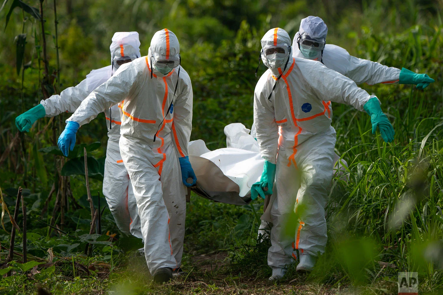 Burial workers dressed in protective gear carry the remains of Mussa Kathembo, an Islamic scholar who had prayed over those who were sick, and died of Ebola, in Beni, Congo, July 14, 2019. (AP Photo/Jerome Delay)
