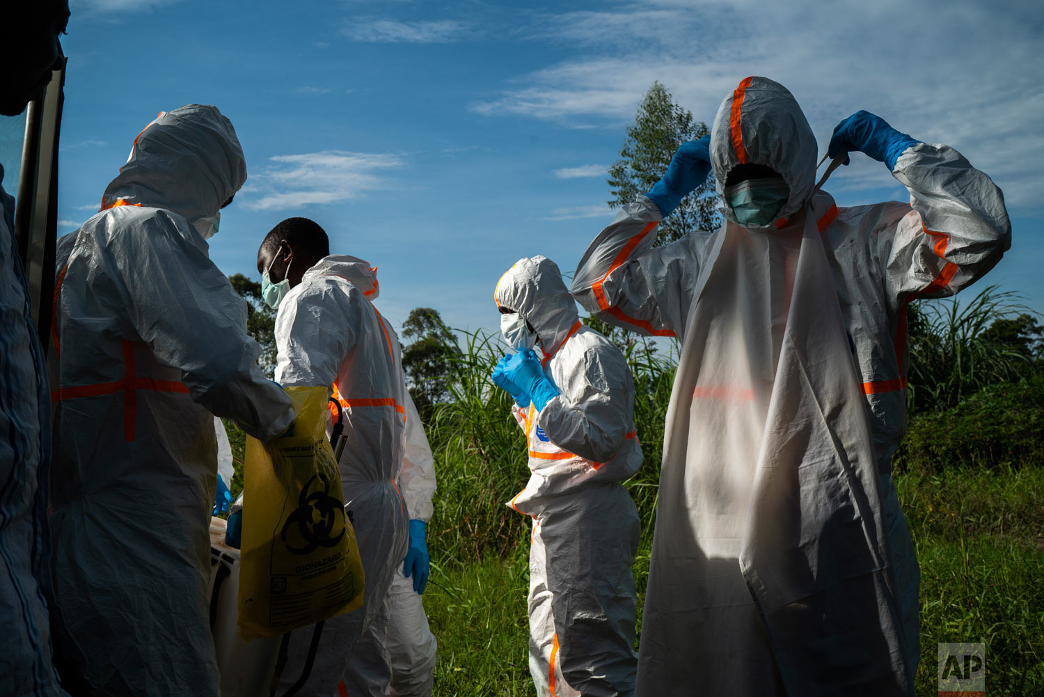 Burial workers put on their protective gear before carrying the remains of Mussa Kathembo, an Islamic scholar who had prayed over those who were sick, and his wife Asiya to their final resting place in Beni, Congo, July 14, 2019. Both died of Ebola. (AP Photo/Jerome Delay)