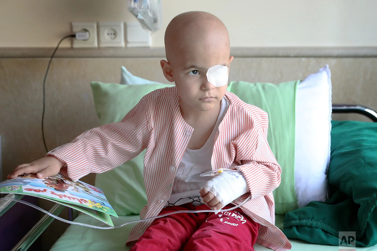 Parsa Amini, a 5-year-old boy suffering from eye cancer, sits on his bed at Mahak Children’s Hospital, in Tehran, Iran. (AP Photo/Ebrahim Noroozi)