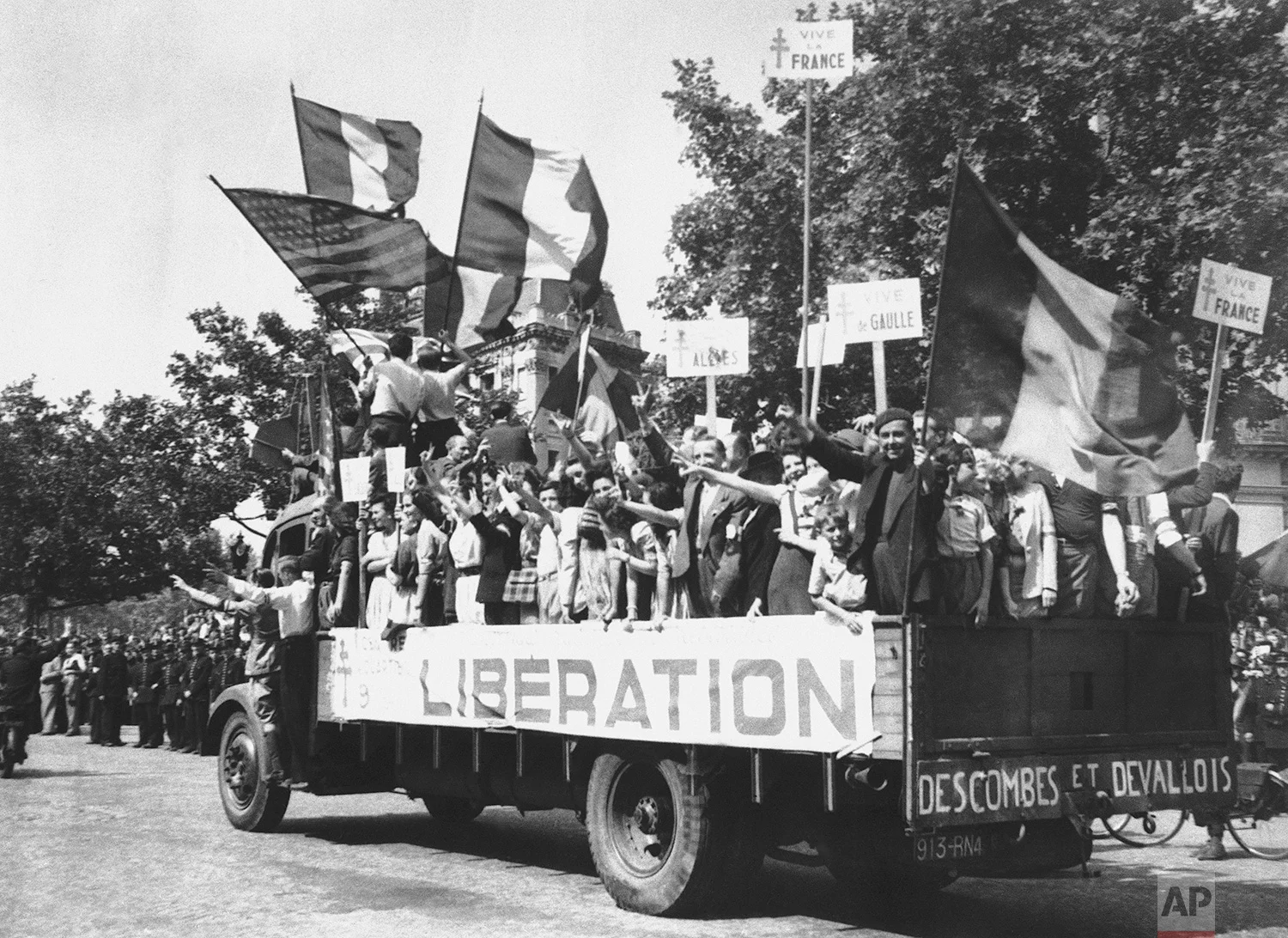 A truck load of Parisians waving flags and carrying Vive De Gaulle banners drives through the streets of a madly rejoicing Paris, on August 28, 1944. (AP Photo/Peter Carroll)