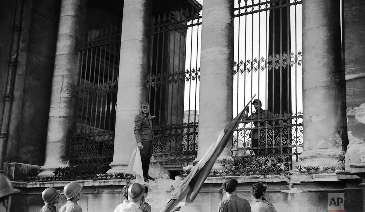 A German officer standing beside one of the columns of the Chamber of Deputies building, in Paris, France on August 30, 1944, holds white flag of truce as he negotiates surrender of German forces within the building with a French soldier carrying the Tricolor. Frenchman waits to hoist flag over the building, where one of the last armed clashes took place before the capital was cleared of the Germans. (AP Photo/Harry Harris)