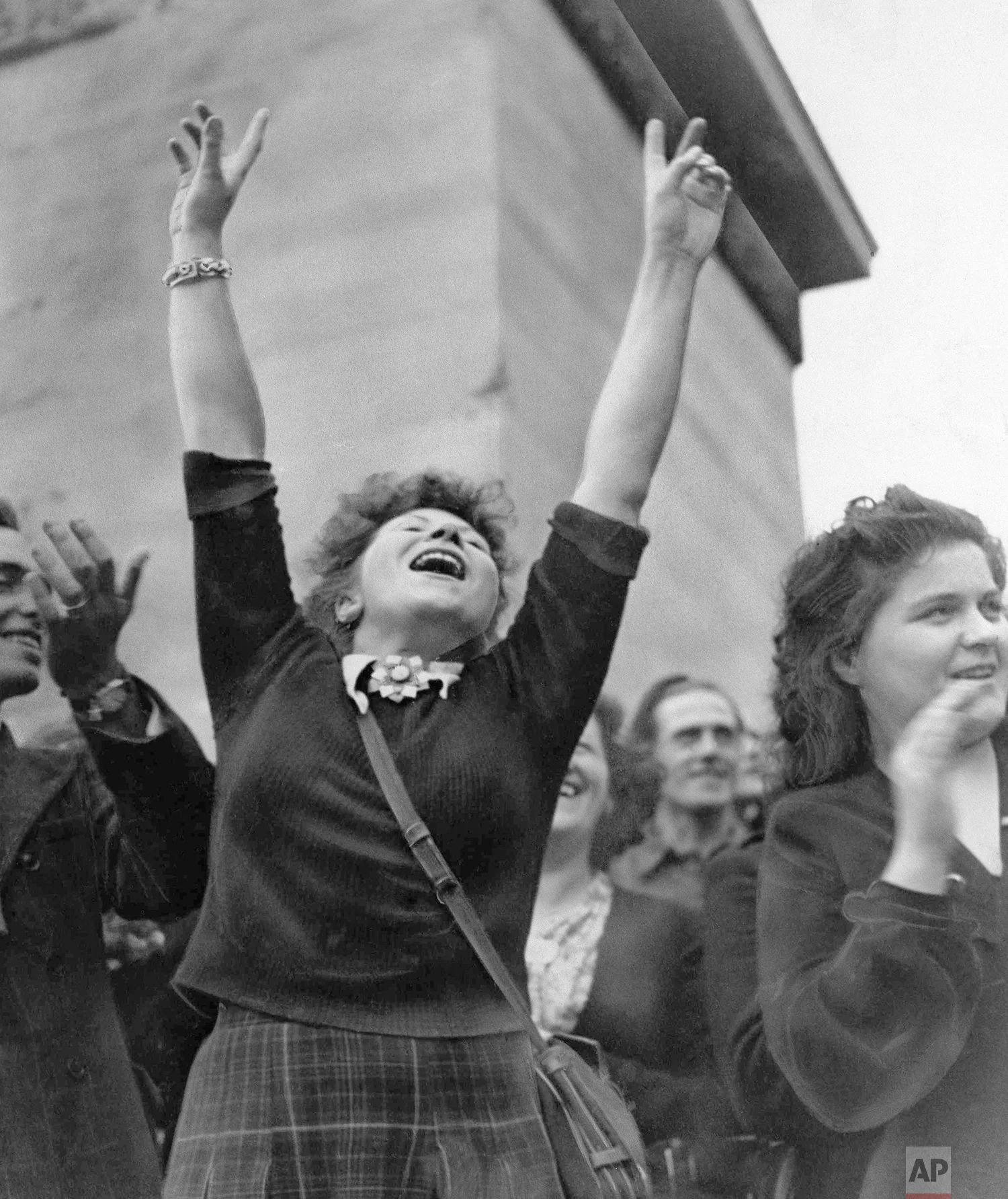 A Parisian girl holds her hands high in the victory sign as American troops pass through Paris, August 25, 1944 on their way to the front after the French capital was liberated. (AP Photo/Richard Boyer)