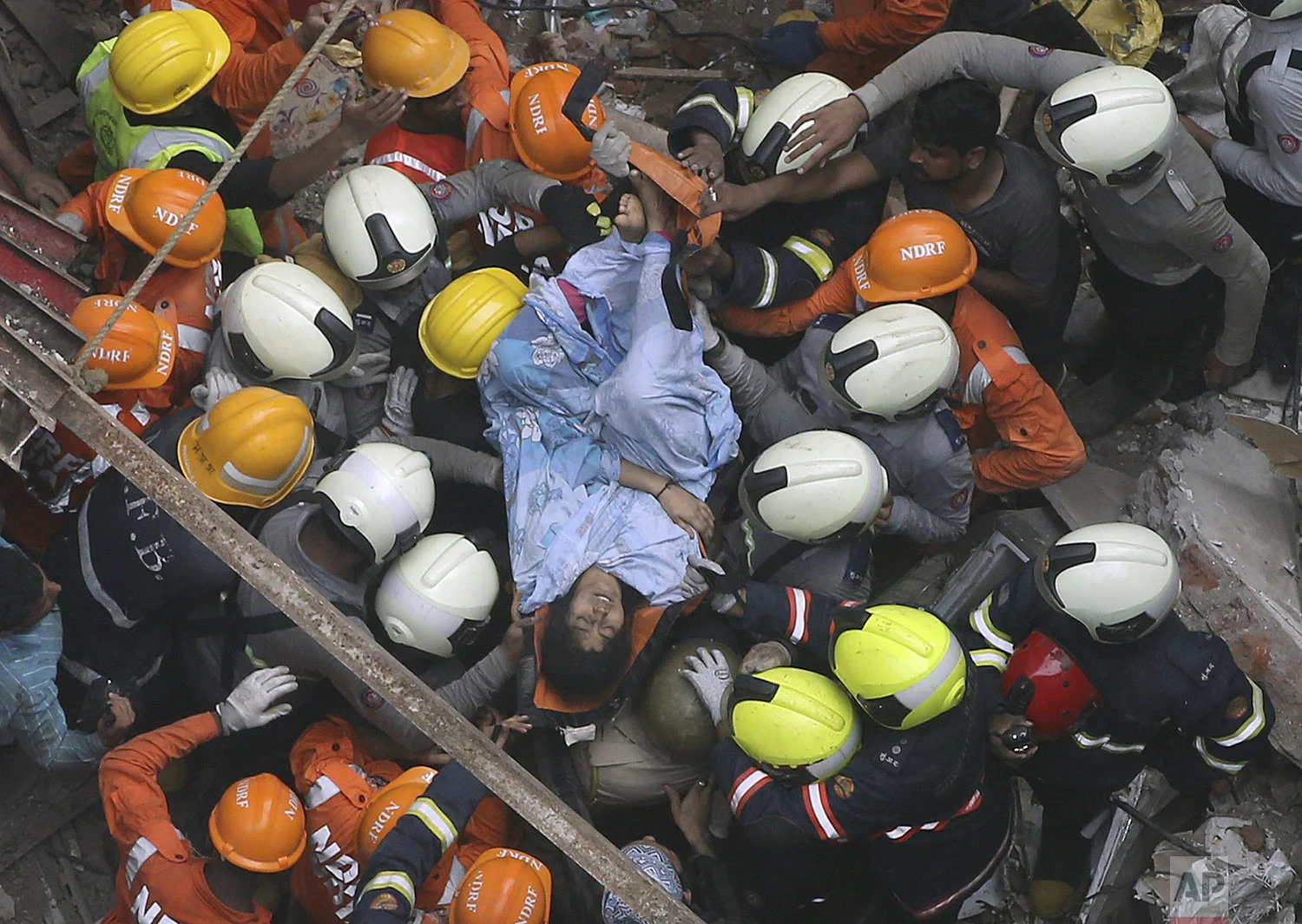 Rescuers carry out a survivor from the site of a building that collapsed in Mumbai, India, Tuesday, July 16, 2019. (AP Photo/Rajanish Kakade)