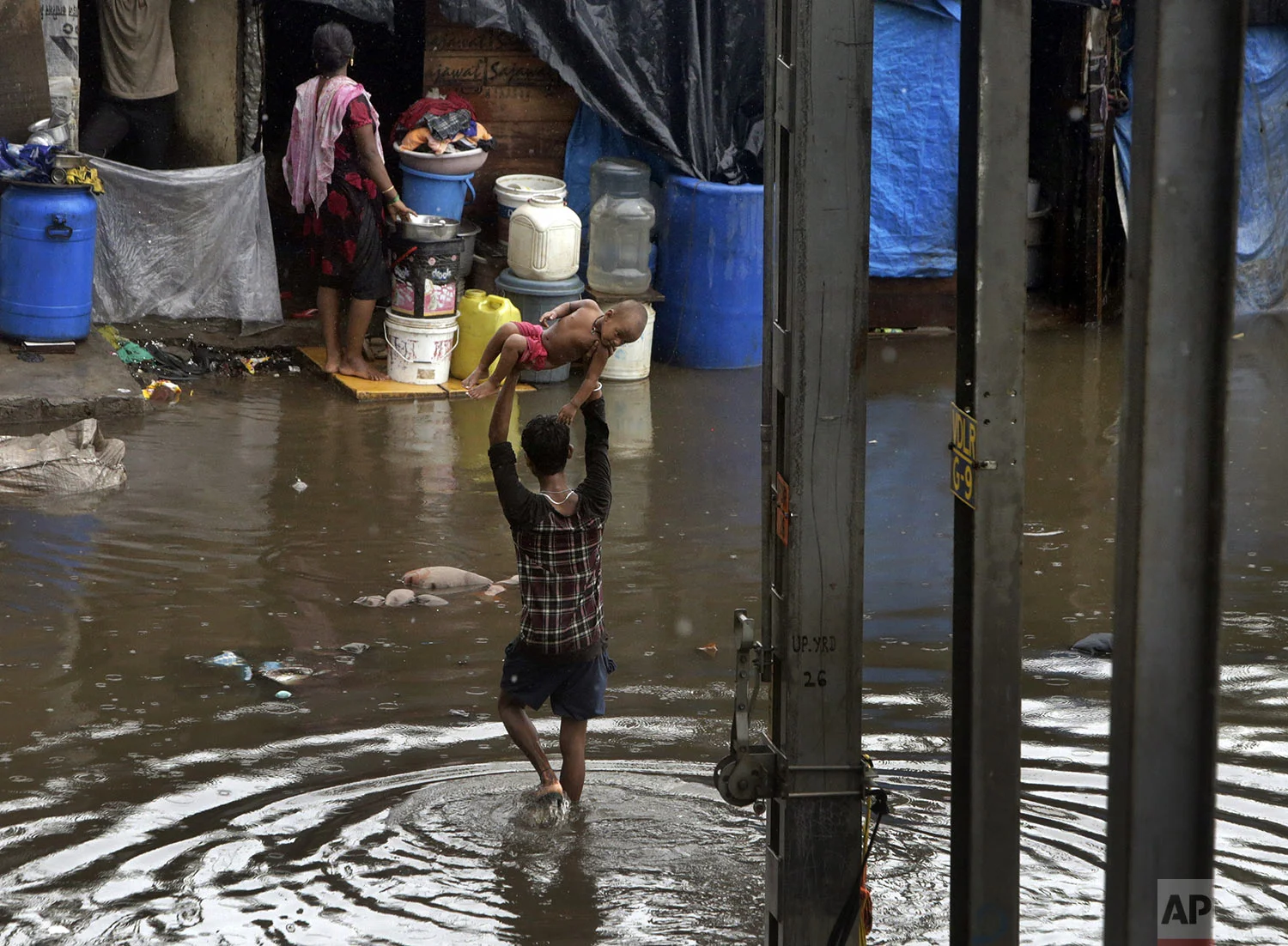 A man holds a child high above his head as he wades through a waterlogged street following heavy rains in Mumbai, India, July 2, 2019. (AP Photo/Rajanish Kakade)