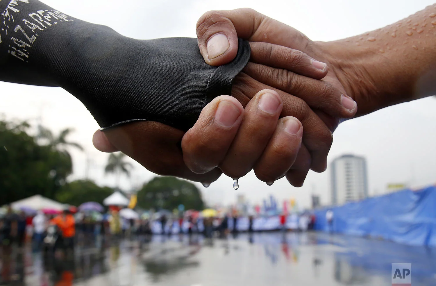 Protesters link hands as they lead a march under the rain towards the Philippine Congress to protest the 4th State of the Nation (SONA) address by President Rodrigo Duterte in suburban Quezon city, northeast of Manila, Philippines, July 22, 2019. (AP Photo/Bullit Marquez)