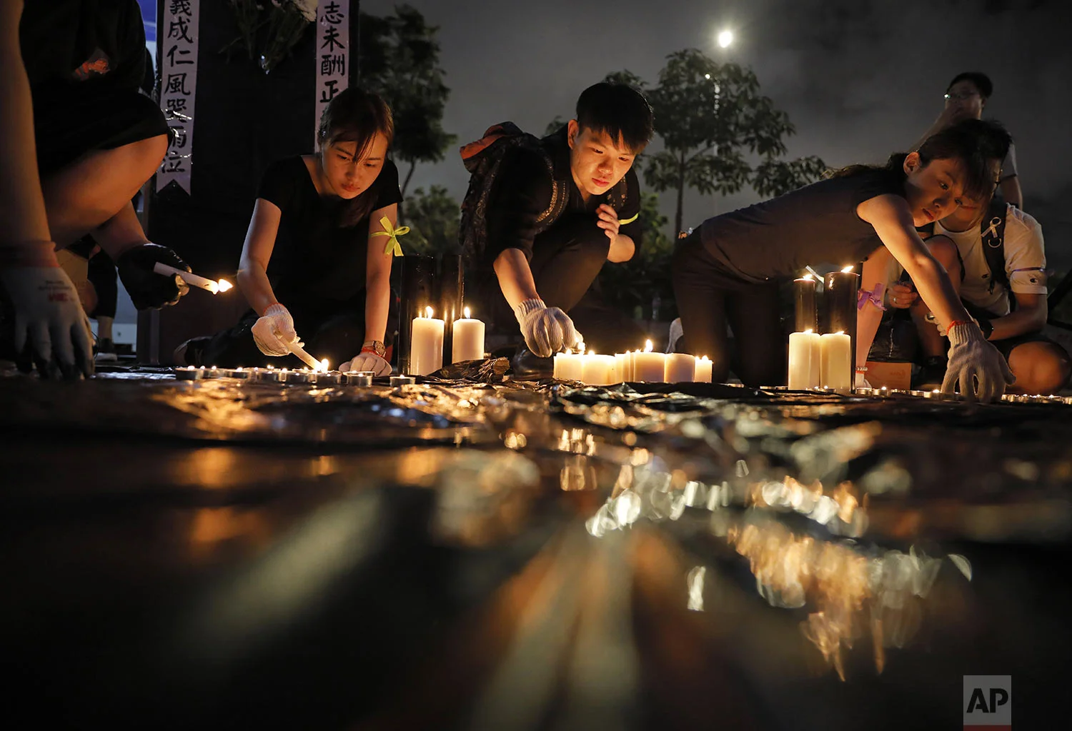 People light candles during a vigil to mourn the recent suicide of a woman due to the government's policy on an extradition bill, in Hong Kong, Saturday, July 6, 2019. (AP Photo/Vincent Yu)
