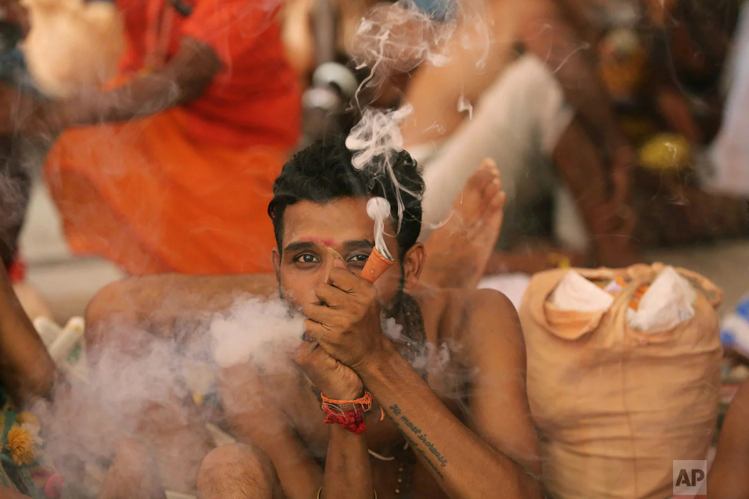 A Hindu holy man smokes as he waits to register for the annual pilgrimage to the Amarnath cave shrine in Jammu, India, July 1, 2019. (AP Photo/Channi Anand)