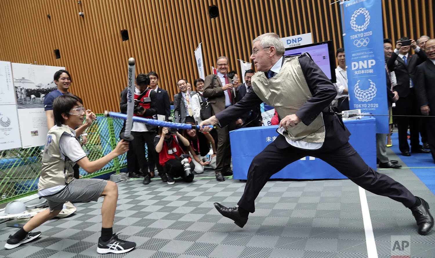 IOC President Thomas Bach, right, demonstrates fencing with Japanese junior high school student Yui Hashimoto during a Olympic Games Tokyo 2020 One year to Go ceremony event in Tokyo, July 24, 2019. (AP Photo/Koji Sasahara, Pool)