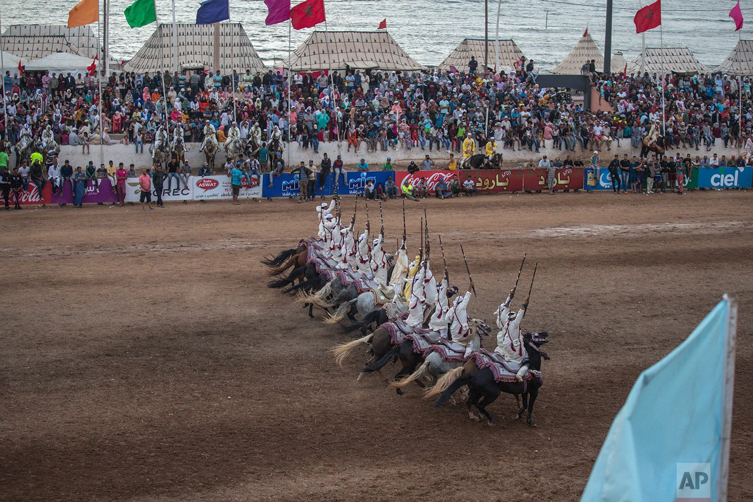 People watch as a troupe charges and fires their rifles during Tabourida, a traditional horse riding show also known as Fantasia, in the coastal town of El Jadida, Morocco, July 25, 2019. (AP Photo/Mosa'ab Elshamy)
