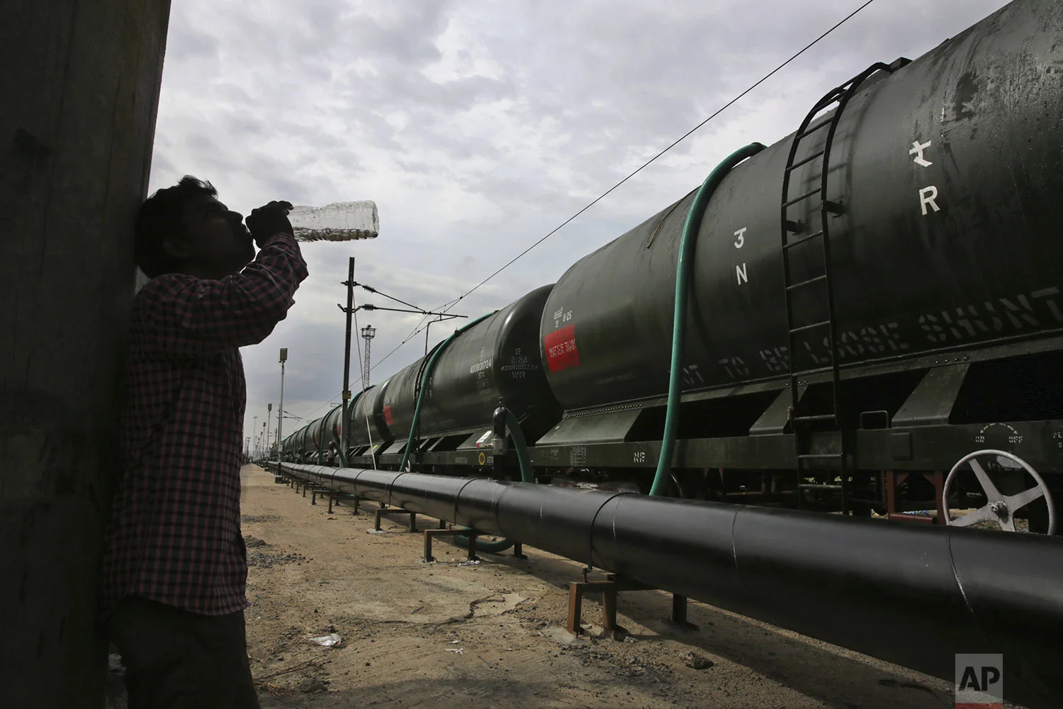 A worker takes a break to drink water while hundreds of hose-pipes are used to fill wagons of a train with drinking water piped through the Mettur dam on the Cauvery River at Jolarpet railway station, 216 kilometers (135 miles) from Chennai in Southern Indian state of Tamil Nadu, Wednesday, July 17, 2019. (AP Photo/Manish Swarup)