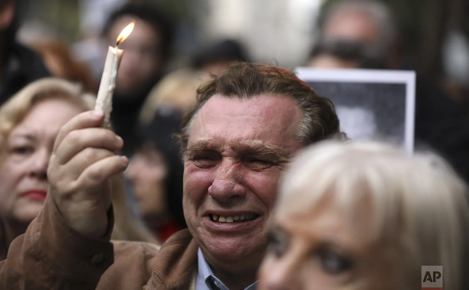 A man cries as he holds up a candle on the 25th anniversary of the bombing of the AMIA Jewish center that killed 85 people in Buenos Aires, Argentina, Thursday, July 18, 2019. (AP Photo/Natacha Pisarenko)