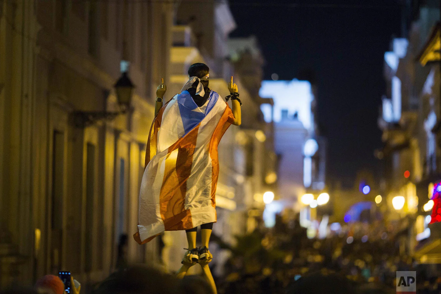 A demonstrator with a Puerto Rican flag reacts during clashes in San Juan, Puerto Rico, Wednesday, July 17, 2019. Thousands of people marched to the governor's residence in San Juan on Wednesday chanting demands for Gov. Ricardo Rossello to resign after the leak of online chats that show him making misogynistic slurs and mocking his constituents. (AP Photo/Dennis M. Rivera Pichardo)