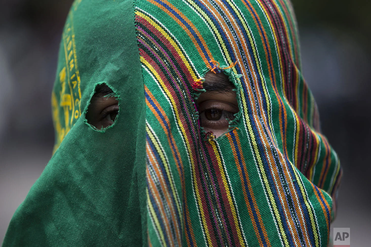 A hooded agronomy student protests outside the hotel where lawmakers are gathered and expected to vote on a deal that Guatemalan President Jimmy Morales' government signed with Washington that would force Salvadoran and Honduran migrants to request asylum in Guatemala instead of the United States, in Guatemala City, Wednesday, July 31, 2019. Critics of the deal point out that Guatemala has the same problems that are driving Hondurans and Salvadorans to flee their homes: violence, poverty, joblessness and a prolonged drought that has severely hurt farmers. (AP Photo/Oliver de Ros)