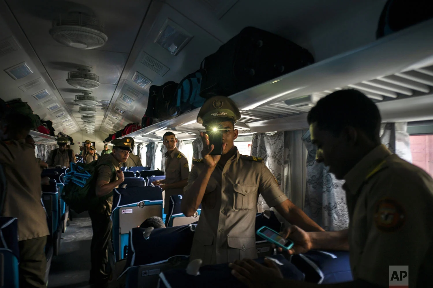 Cuban cadets board the first train using new equipment from China, in Havana, Cuba, Saturday, July 13, 2019. The first train using new equipment from China pulled out of Havana Saturday, hauling passengers on the start of a 915-kilometer (516-mile) journey to the eastern end of the island as the government tries to overhaul the country's aging and decrepit rail system. (AP Photo/Ramon Espinosa)