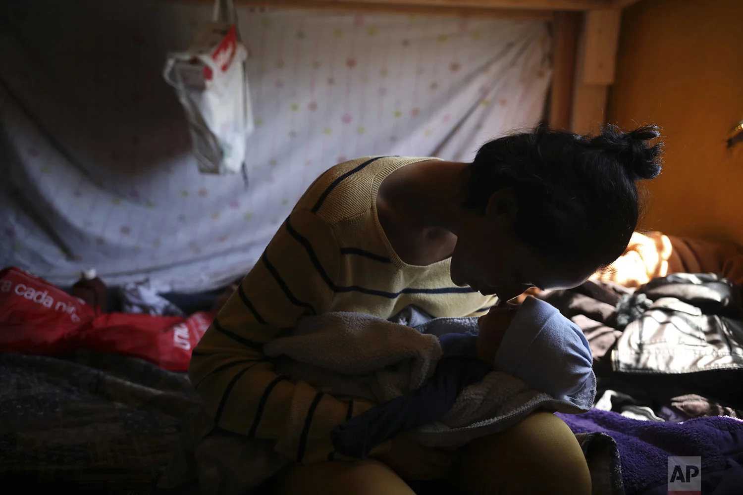 Salvadoran teen migrant Milagro de Jesus Henriquez Ayala nuzzles with her newborn son Alexander, at the Agape World Mission shelter, in Tijuana, Mexico, June 12, 2019. Henriquez Ayala has finished the paperwork for a Mexican visa and is determined to build a life on the south side of the U.S.-Mexico border, though the lanky girl has no idea how she'll do that. (AP Photo/Emilio Espejel)