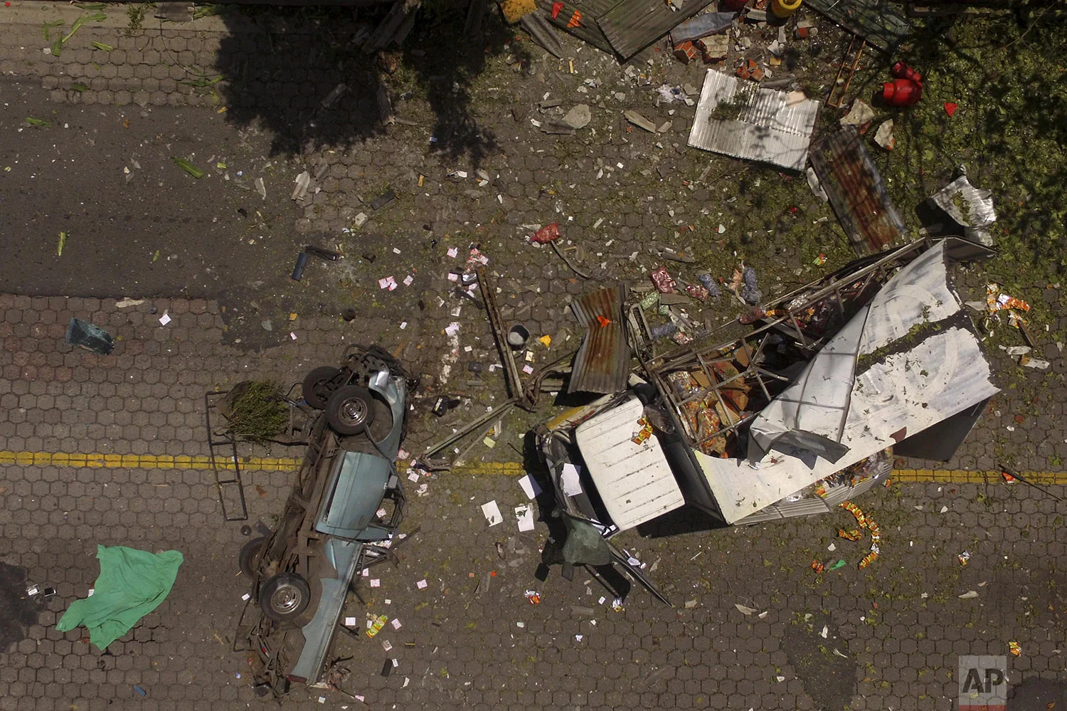 Trucks and debris lie scattered after a deadly explosion of propane gas cylinders at a depot in Mejicanos, El Salvador, Friday, July 12, 2019. Defense Minister Rene Merino visiting the site said that early indications suggested the explosion was accidental, but that authorities are still investigating any possible connection to terrorism by the gangs. (AP Photo/Salvador Melendez)