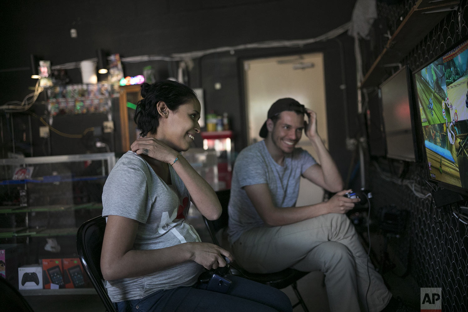  In this May 23, 2019 photo, pregnant teen migrant, Milagro de Jesus Henriquez Ayala plays video games with her friend, Ivan Duran Avila, at a small shopping plaza in Tijuana, Mexico. (AP Photo/Emilio Espejel) 