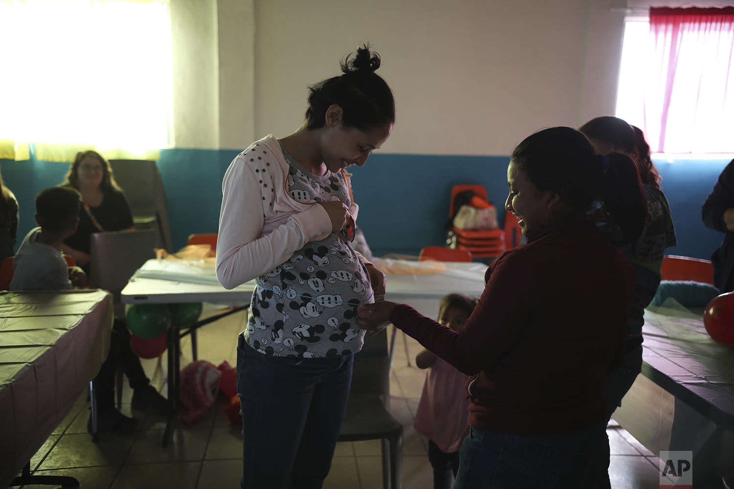  In this May 25, 2019 photo, Salvadoran teen migrant Milagro de Jesus Henriquez Ayala has her pregnant belly measured with a piece of string by a fellow migrant, during her baby shower at a hall in Tijuana, Mexico. (AP Photo / Emilio Espejel) 