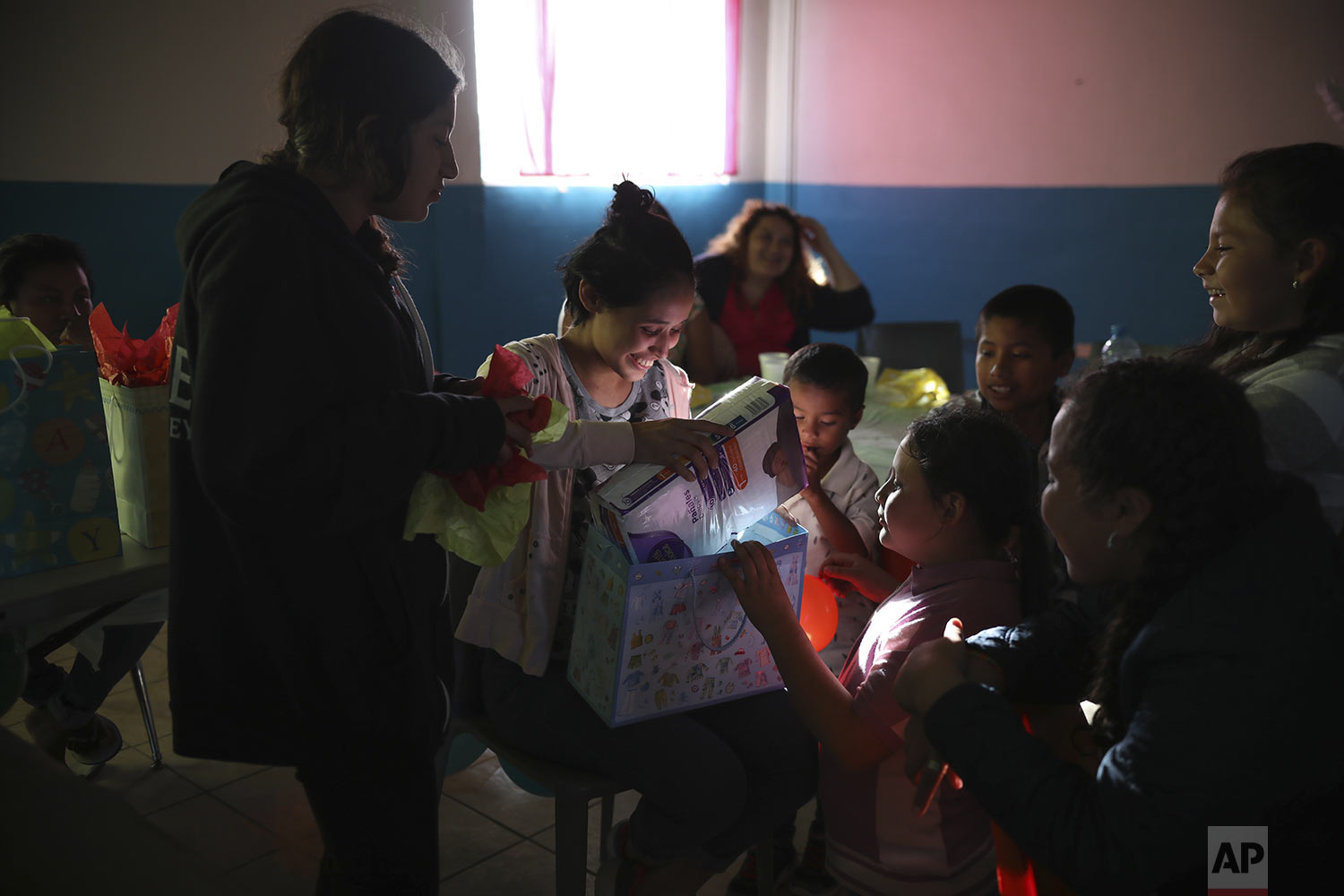  In this May 25, 2019 photo, Salvadoran teen migrant Milagro de Jesus Henriquez Ayala, opens her gifts during her baby shower at at a meeting hall in Tijuana, Mexico.  (AP Photo/Emilio Espejel) 