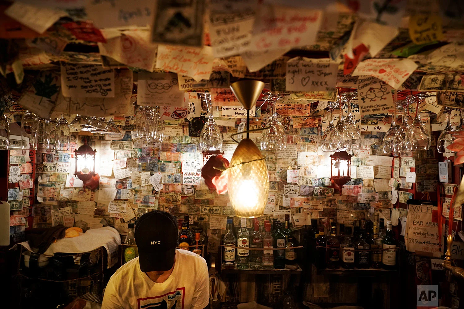A bartender fixes a drink in a bar decorated with thousands of messages written by patrons at the Golden Gai in the Shinjuku district of Tokyo, July 26, 2019. (AP Photo/Jae C. Hong)