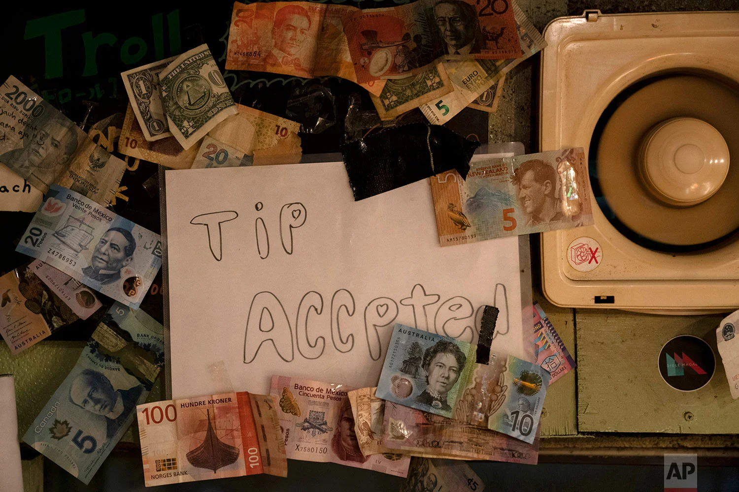 A sign is posted on the wall clustered with bills from various countries in a bar at the Golden Gai in the Shinjuku district of Tokyo, July 17, 2019. (AP Photo/Jae C. Hong)