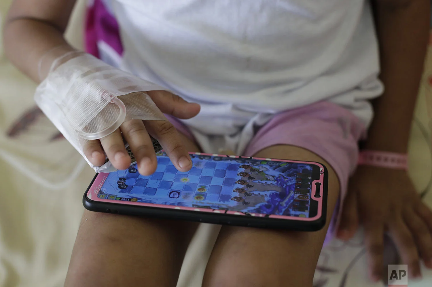 A young dengue patient plays with a smartphone as she stays inside the San Lazaro government hospital in Manila, Philippines on Wednesday, Aug. 7, 2019. (AP Photo/Aaron Favila)