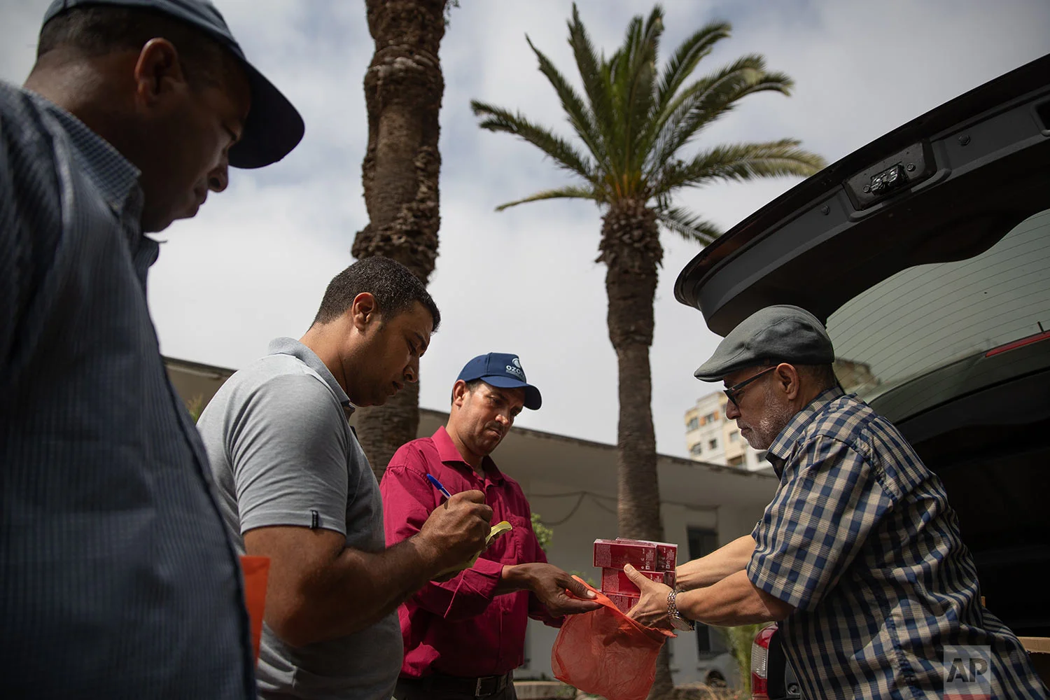 Habib El Ghazaoui, right, a father who runs the Association for Solidarity with Children of the Moon, distributes topical cream to parents of children affected by a rare disorder called xeroderma pigmentosum, or XP, inside a hospital in Casablanca, Morocco, July 24, 2019. (AP Photo/Mosa'ab Elshamy)