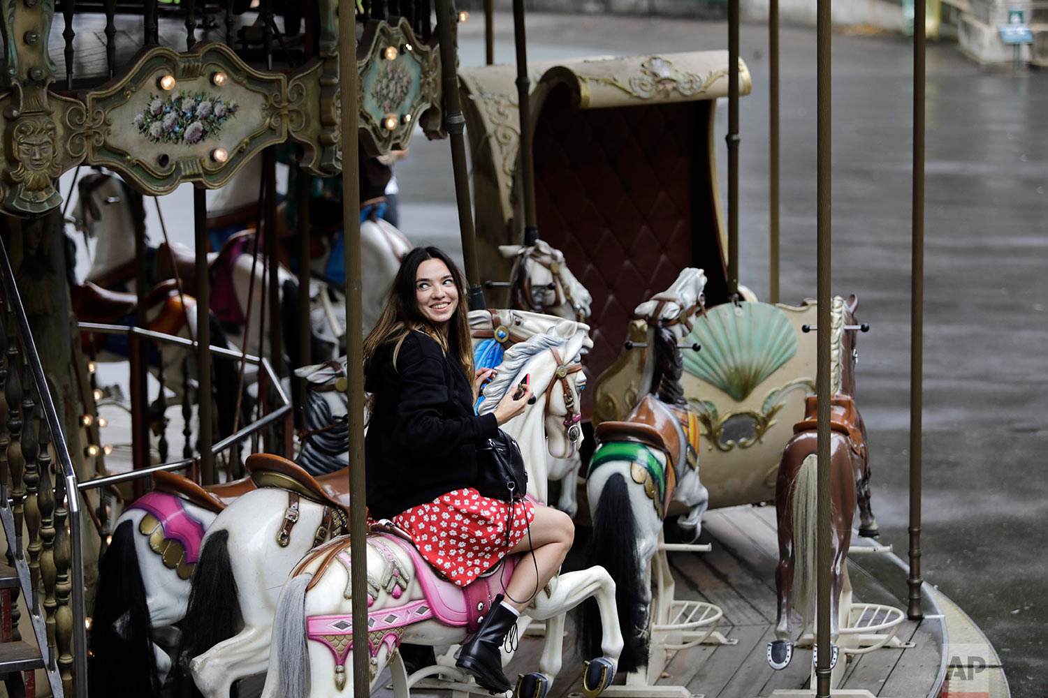  A woman smiles as she takes a ride on a carousel in the Montmartre district of Paris Friday, Aug. 9, 2019. (AP Photo/Lewis Joly) 