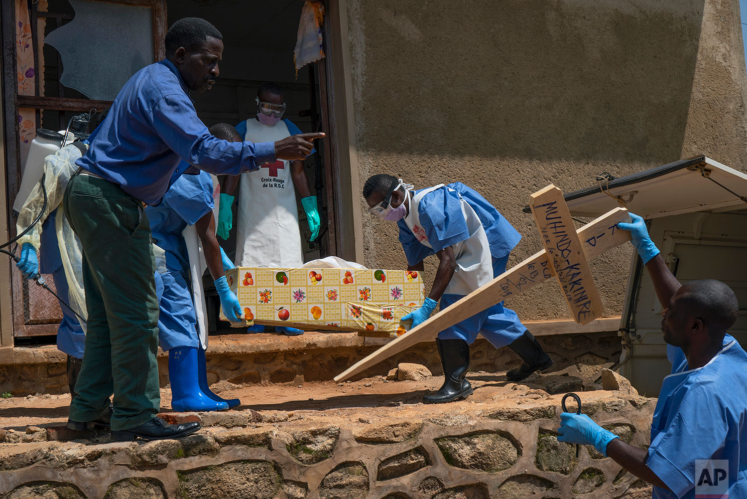 In this July 14, 2019 photo, Red Cross workers carry the remains of 16-month-old Muhindo Kakinire rom the morgue into a truck as health workers disinfect the area in Beni, Congo DRC. (AP Photo/Jerome Delay)