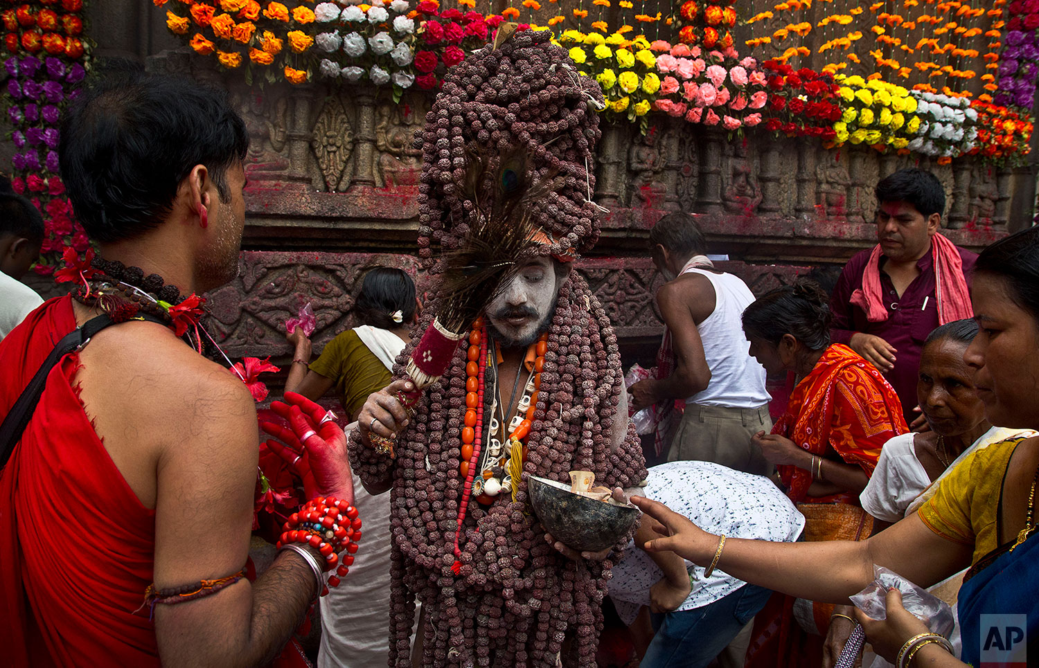 A Sadhu, or Hindu holy man, blesses devotees during Ambubachi festival at Kamakhya templein Gauhati, India, June 25, 2019 . The temple is presided over by the goddess Kamakhya, the most important goddess of tantric worship, an esoteric form of Hinduism. The four-day Ambubachi festival is a celebration of Kamakhya's yearly menstrual cycle, and it brings hundreds of thousands of devotees to the temple. (AP Photo/Anupam Nath)