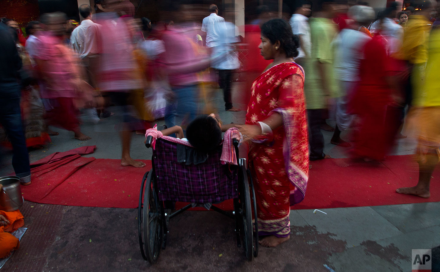 Monika Deb Nath, 45, stands beside her son Gopal, 17, at the Kamakhya temple during the Ambubachi festival in Gauhati, India, June 25, 2019 . Monika, 45, and her husband have visited the Kamakhya temple four years in a row for the annual Ambubachi festival, praying for a miracle to heal their son from cerebral palsy, which has left him with almost no control over his own body. The temple is presided over by the goddess Kamakhya, the most important goddess of tantric worship, an esoteric form of Hinduism.(AP Photo/Anupam Nath)