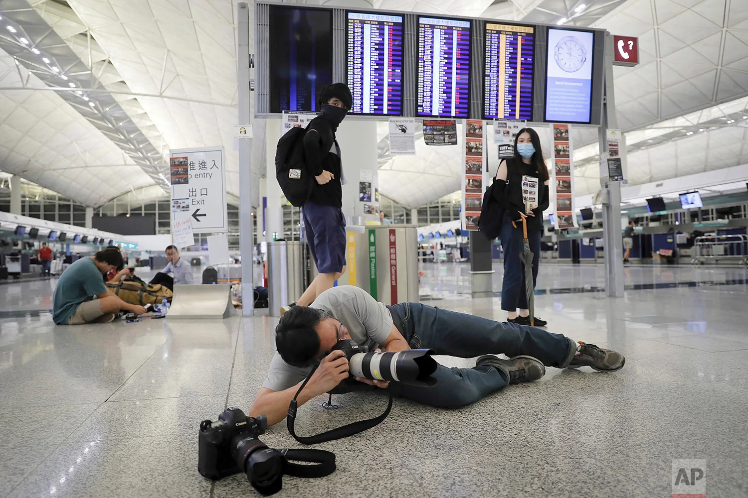 AP photographer Vincent Thian takes photos of stranded travelers after authorities canceled all flights at the Hong Kong International Airport in Hong Kong, Aug. 12, 2019. (AP Photo/Kin Cheung)