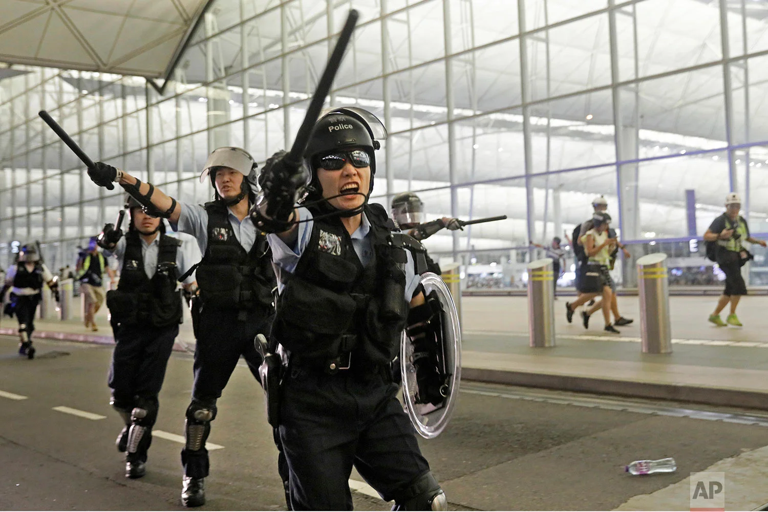 Policemen with batons and shields shout at protesters during a demonstration at the Airport in Hong Kong, Aug. 13, 2019. (AP Photo/Vincent Yu)