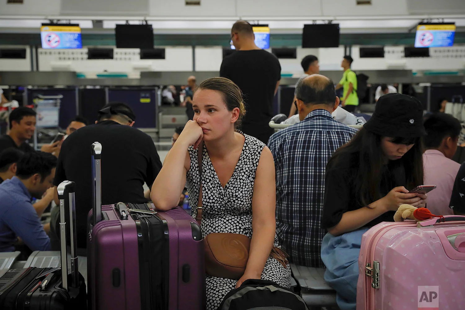 Australian Penny Tilley, center, reacts next to stranded travelers at the closed check-in counters at the Hong Kong International Airport, Monday, Aug. 12, 2019. (AP Photo/Kin Cheung)