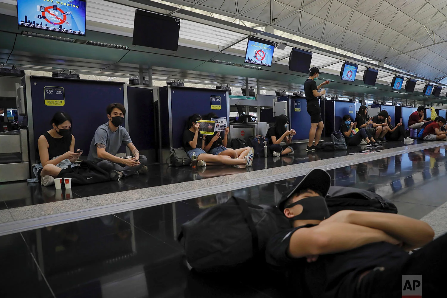 Protesters gather at the closed check-in counters at the Hong Kong International Airport, Aug. 12, 2019. (AP Photo/Kin Cheung)