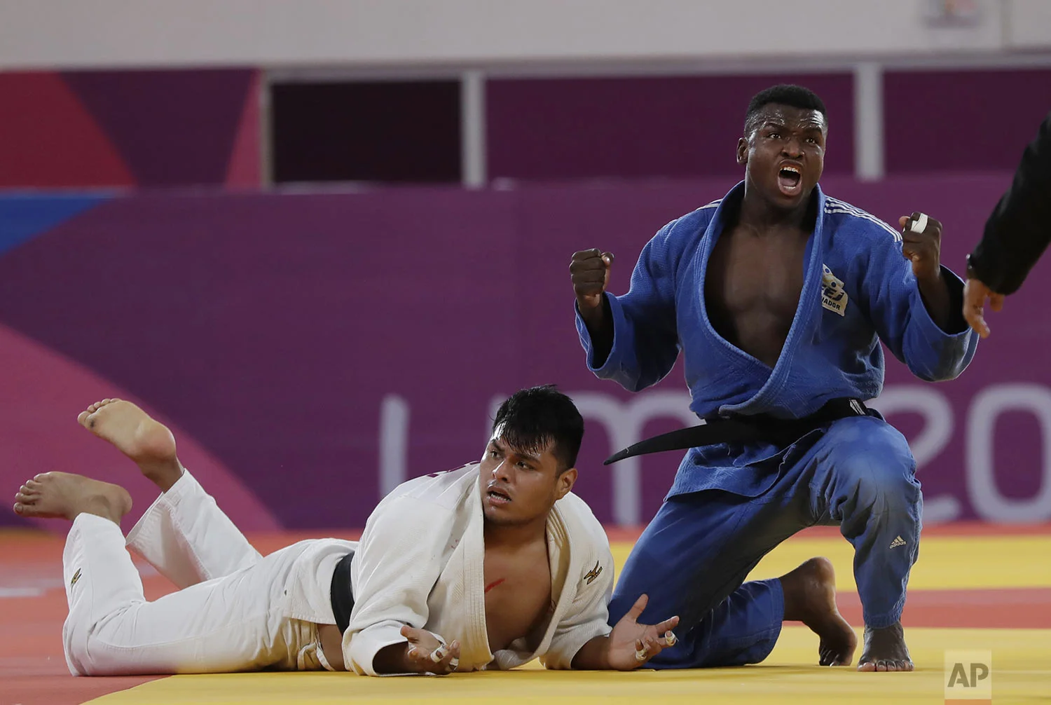 Junior Angulo of Ecuador, right, celebrates after beating Jose Arroyo of Peru in the men's - 100kg bronze medal judo match at the Pan American Games in Lima Peru, Sunday, Aug.11, 2019. (AP Photo/Silvia Izquierdo)