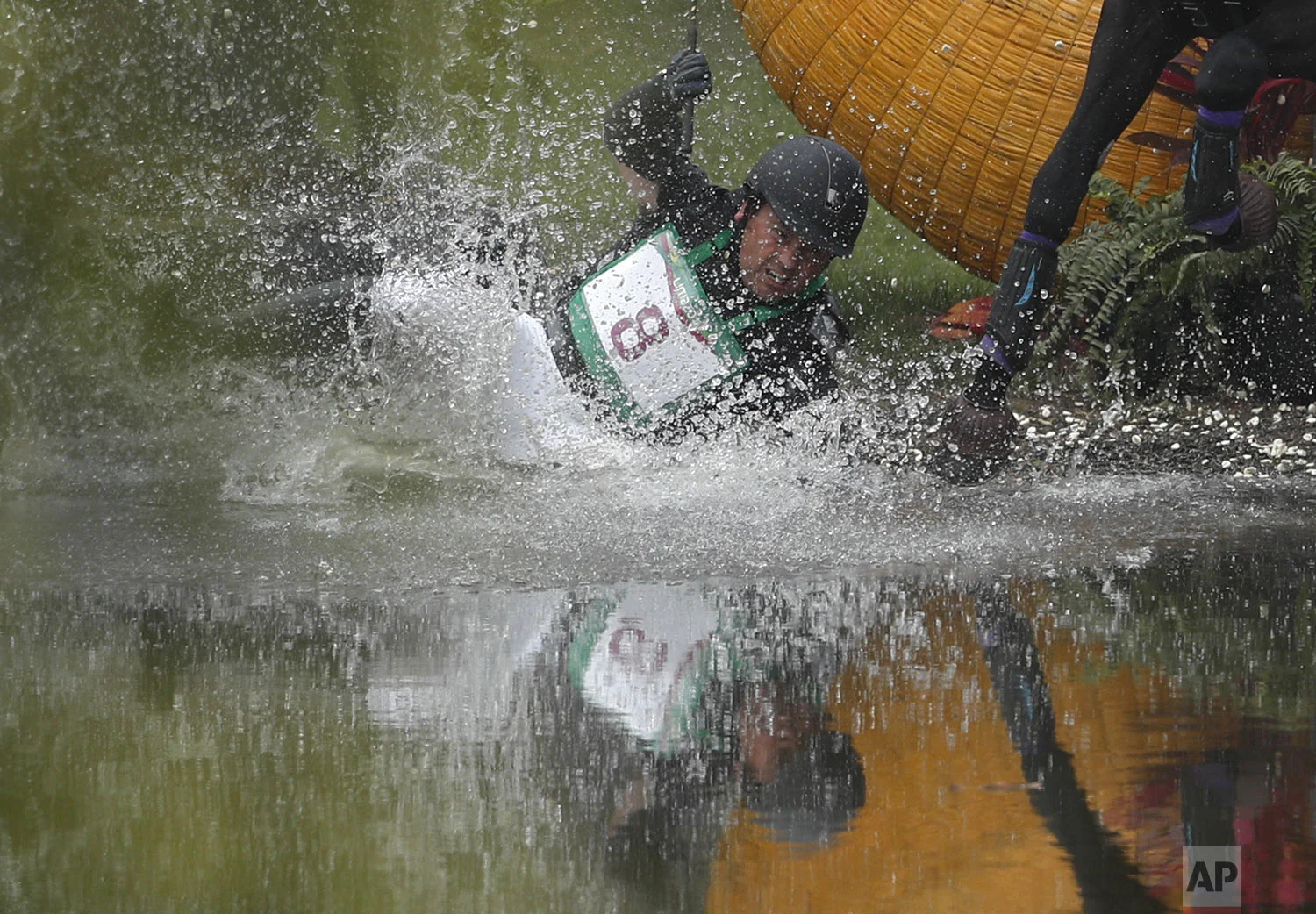Colombia's Mauricio Bermudez lands in the water after being thrown when his horse Fernhill Nightshift tripped while crossing a jump, in the cross country discipline of equestrian eventing at the Pan American Games in Lima, Peru, Saturday, Aug. 3, 2019. (AP Photo/Rebecca Blackwell)