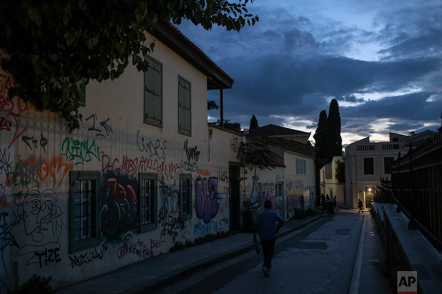 A man walks next to graffiti covered houses in Plaka district, Athens, July 3, 2019. (AP Photo/Petros Giannakouris)