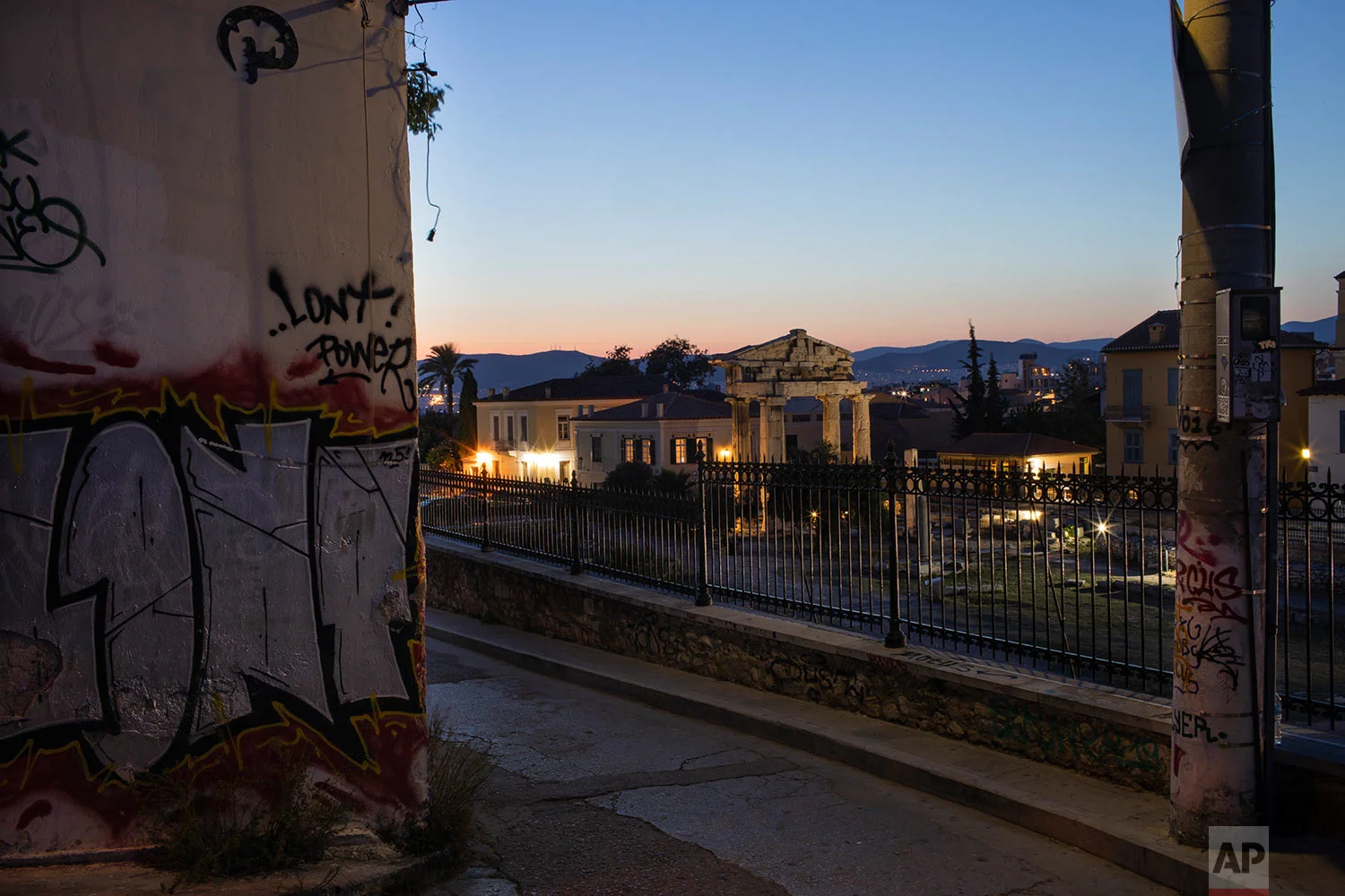 The facade of a building and an electricity pole are covered with graffiti in front the Gate of the ancient Roman agora in Plaka district of Athens, July 7, 2019. (AP Photo/Petros Giannakouris)