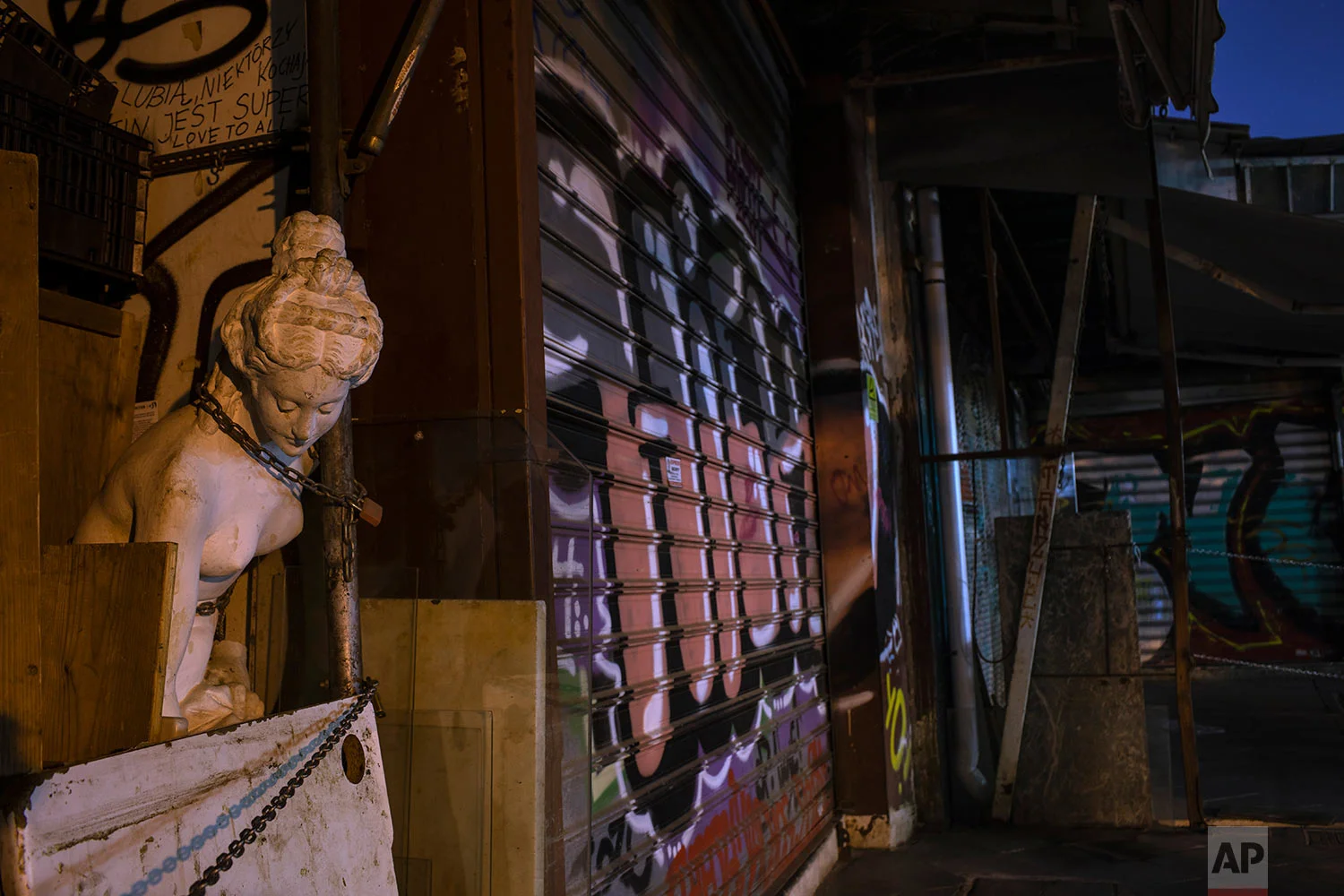 A modern copy of a statue of Aphrodite, ancient Greek Goddess of beauty, is chained to a wall outside a closed antique shop as shutters of other shops are covered with graffiti in Monastiraki district, central Athens, July 22, 2019. (AP Photo/Petros Giannakouris)