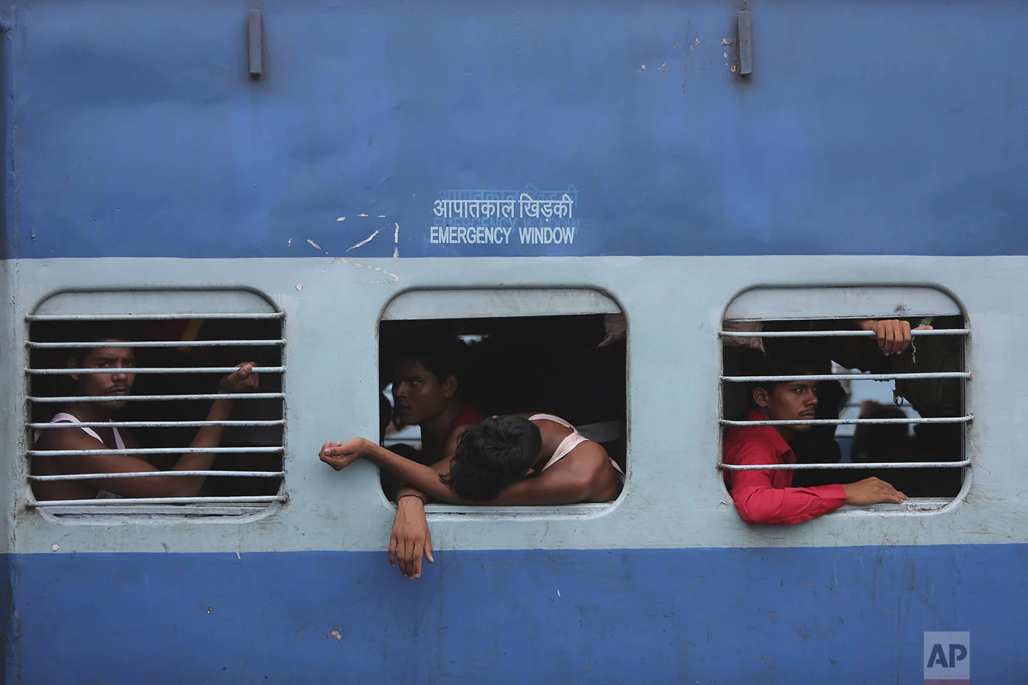 Indian migrant laborers sit inside a train as they prepare to leave the region, at a railway station in Jammu, India, Wednesday, Aug. 7, 2019. (AP Photo/Channi Anand)